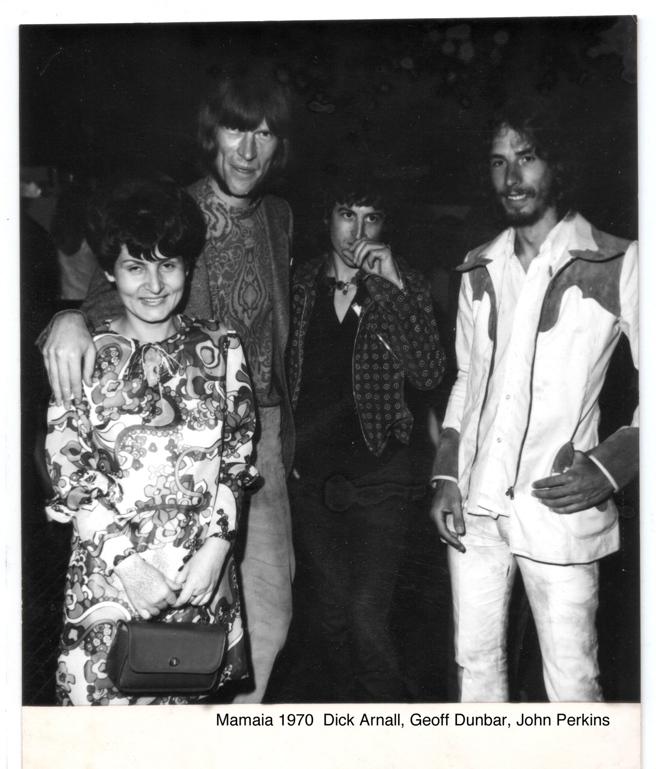 Dick Arnall, Geoff Dunbar and John Perkins standing with an unidentified woman in a patterned dress at Mamaia